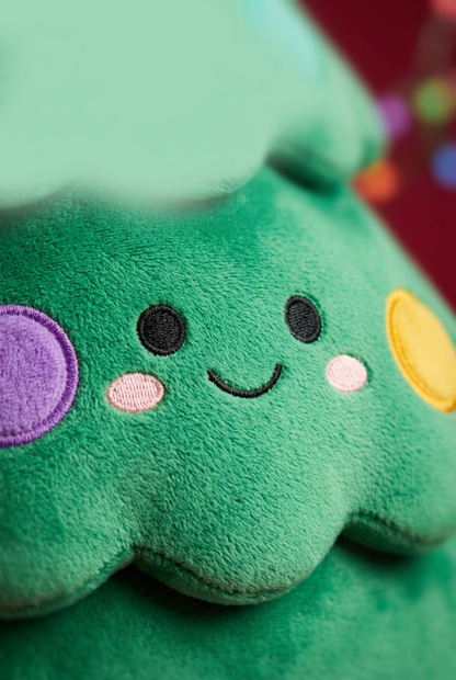 Close-up of the smiling face and pink cheeks on the green plush tree